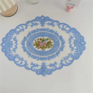 Detailansicht der feinen Blumenstickerei und der blauen Spitze eines Deko-Platzdeckchens