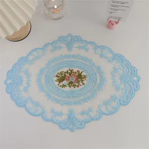 Detailansicht eines blau gestickten Spitzendeckchens mit floralem Mittelstück Design