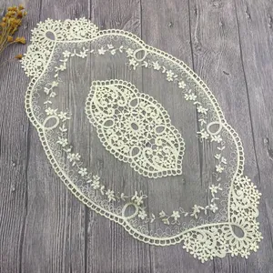 Primer plano de un elegante camino de mesa de encaje crema con bordado floral calado.