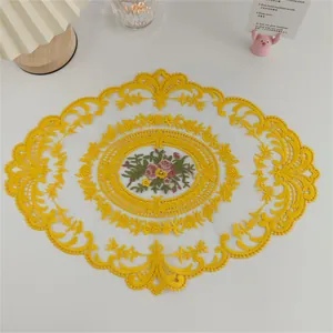 Detailansicht eines gelb bestickten Spitzen-Tischsets mit Blumenmuster auf dem Tisch