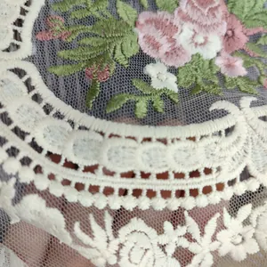 Nahaufnahme der exquisiten Rosenstickerei und der zarten weißen Spitze auf dem Tischset