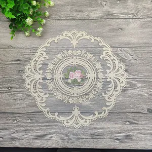 Detailansicht der Blumenstickerei und Spitze auf einem runden camel Platzset