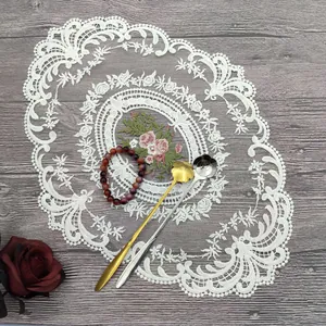 Detailansicht weißes besticktes Tischset aus Spitze mit Rosenmuster auf Holzgrund