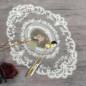 Nahaufnahme des eleganten weißen Spitzen-Platzsets mit Blumenstickerei auf Holz
