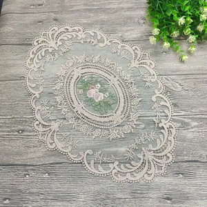 Detaillierte Nahaufnahme eines beigen Spitzen-Tischsets mit rosa Blumenstickerei im europäischen Stil
