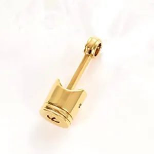 Macro view of a gold-plated stainless steel piston-shaped cremation urn pendant for ashes.