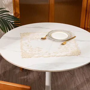 Elegante tovaglietta in pizzo con ricamo floreale esposta su un tavolo da pranzo in marmo bianco.