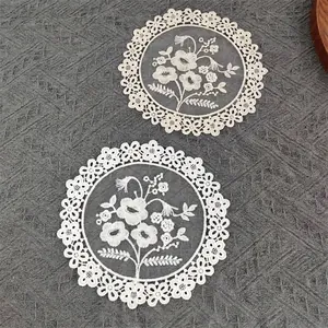 Close-up of white mesh placemats featuring intricate floral embroidery and lace edges