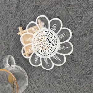 Close-up of white mesh embroidered circular coaster with delicate floral lace pattern