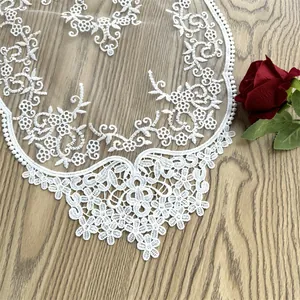 Detailansicht eines eleganten weißen Spitzen-Tischläufers mit feiner Blumenstickerei