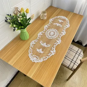 Detailed view of white lace embroidered table runner on a wooden dining table