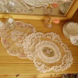 Detailed view of vintage mesh lace placemat with delicate pink floral embroidery on wood