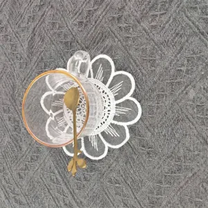 Close-up detail of a white lace embroidered round coaster with elegant flower petal design