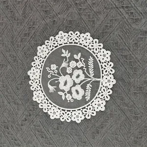 Macro detail of a white circular embroidered mesh coaster with floral lace patterns