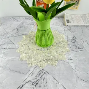 Vintage French lace placemat with floral embroidery under a green vase on marble.
