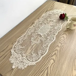 Eleganter weißer Tischläufer aus Spitze mit Blumenstickerei auf einem rustikalen Holztisch