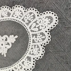 Detailed view of intricate white floral embroidery on a hollowed-out mesh coaster.