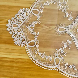 Detailed close-up of elegant cream lace embroidery and delicate mesh on a wooden table