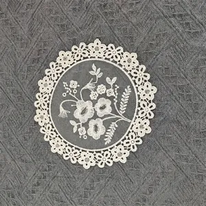 Detailed macro view of intricate white mesh embroidered floral lace coaster for table
