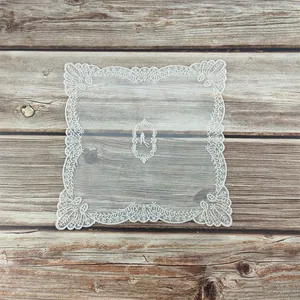 Detailweergave van vierkante witte kanten placemat met bloemig borduurwerk op hout