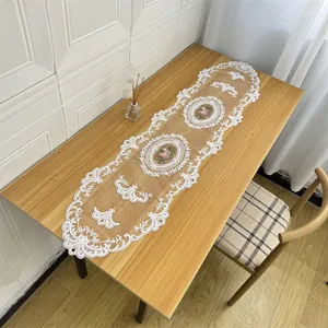Detailed view of white lace embroidery table runner with floral patterns on wood