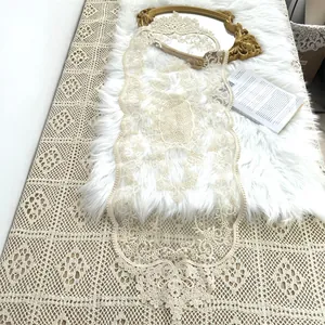 Detailansicht eines eleganten cremefarbenen Spitzen-Tischläufers mit Blumenmuster.