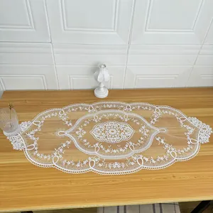 Elegant white lace embroidered table runner with intricate floral patterns on wooden table