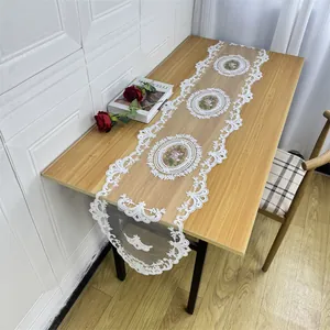 Elegant white lace embroidered table runner with floral patterns on a wooden table
