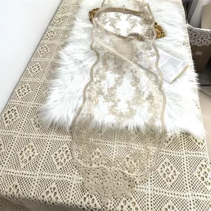 Detail eines beige bestickten Spitzen-Tischläufers im europäischen Stil auf weißem Kunstfell