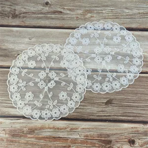 Detailopname van elegante witte kanten kleedjes met bloemenborduurwerk op hout