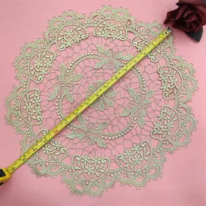 Detailed view of round embroidered lace doily with measuring tape showing diameter.