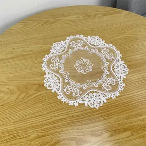 Elegant round white embroidered lace doily on wooden table surface