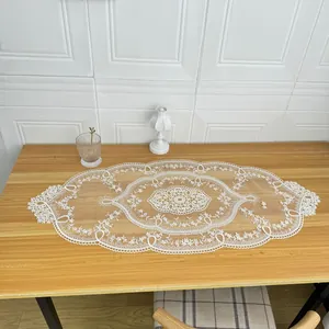 Elegant oval white lace table runner with intricate floral embroidery on wood table
