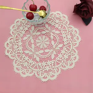Close-up of intricate floral embroidery on a cream-colored round lace placemat
