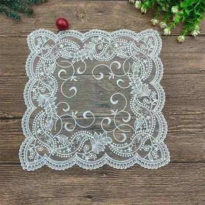 Elegante tovaglietta in pizzo bianco ricamato con motivi floreali su tavolo di legno