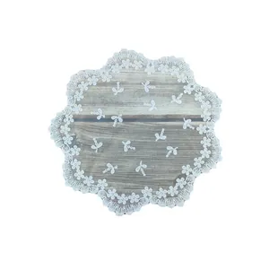 Elegante witte ronde kanten placemat met bloemenborduursel op houten achtergrond