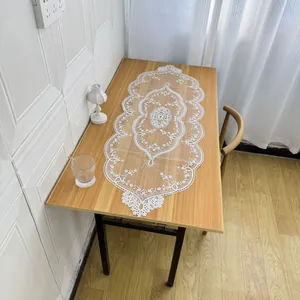 Detailed top view of a white lace table runner with intricate floral embroidery on wood