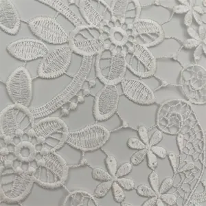 Close-up of white floral lace embroidery texture on a decorative table runner.