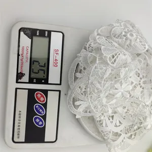 Detailed macro view of a white lace coaster on a scale showing a weight of 25g.