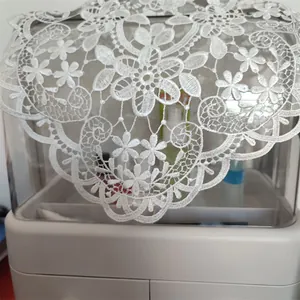 Close-up of intricate white floral lace embroidery on a decorative table runner.