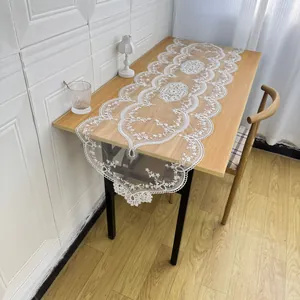Detailed view of white floral lace table runner with intricate embroidery and scalloped edges