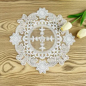 Detailed white embroidered lace doily with floral patterns on a light wooden background