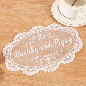 Close-up detail of vintage white lace coaster with Healthy and Happy embroidery on wood