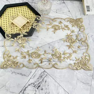 Intrincado bordado de rosas doradas en mantel individual de encaje con bordes festoneados.