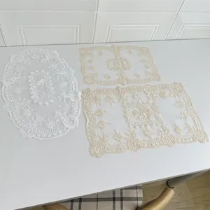 Detailansicht der aufwendigen Blumenstickerei auf cremefarbenen Tischsets aus Netzstoff