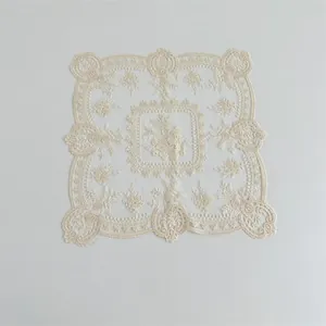 Nahaufnahme eines eleganten cremefarbenen Spitzenuntersetzers mit feiner Blumenstickerei