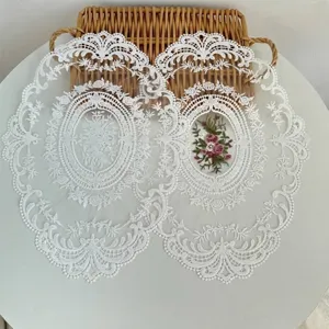 Gedetailleerd overzicht van witte kanten placemats met delicaat bloemenborduurwerk.