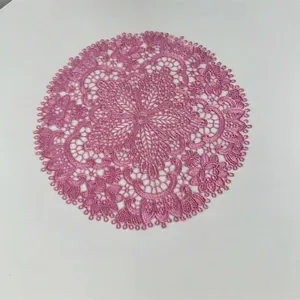 Detailed view of a round pink embroidered lace placemat with delicate floral patterns