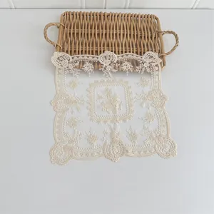 Detailaufnahme eines cremefarbenen Spitzenuntersetzers mit floraler Stickerei und Wellenrand