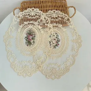Detail van een crèmekleurige kanten placemat met bloemenborduurwerk en schulprand